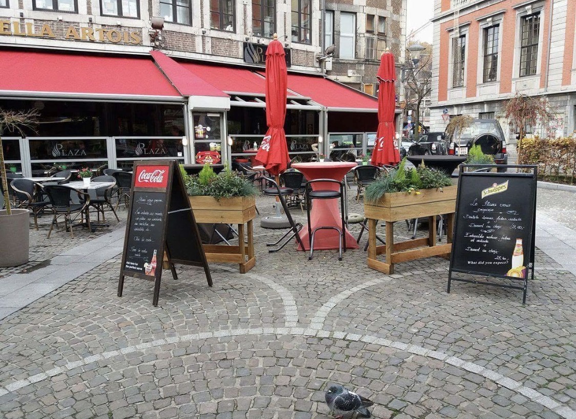 Façade et terrasse du Plaza avec ses stores rouges, sur la place pavée à côté de l'Hôtel-de-Ville de Liège